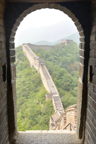 La gran muralla miraba desde un puesto de guardia. Enmarcado por una puerta desde el puesto de observación. Escaleras que ahorran un enorme desnivel. Sección Mutianyu, Pekín, China — Foto de Stock
