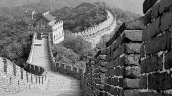 El camino de la gran muralla zigzagueando a través de la montaña y cruzando varios puestos de guardia. En el fondo hay una pareja cogida de la mano. Sección Mutianyu, Beijing, China. Blanco y negro — Foto de Stock