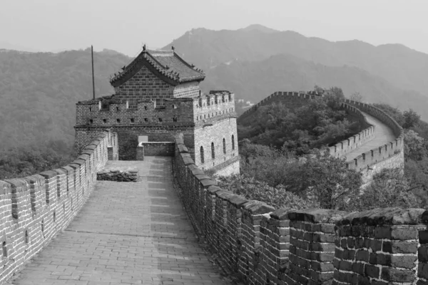 Camino de la gran muralla zigzagueando a través de las montañas, que conduce a un puesto de guardia. Sección Mutianyu, Beijing, China. Fotografía en blanco y negro . — Foto de Stock