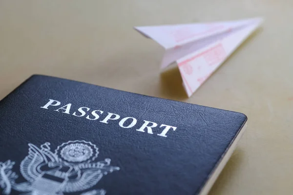 Pasaporte sobre la mesa y plegado desde avión de papel — Foto de Stock