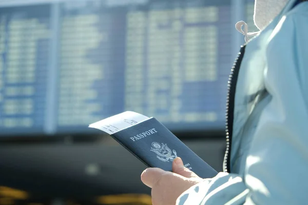 Mujer con pasaporte mirando a bordo de salida — Foto de Stock