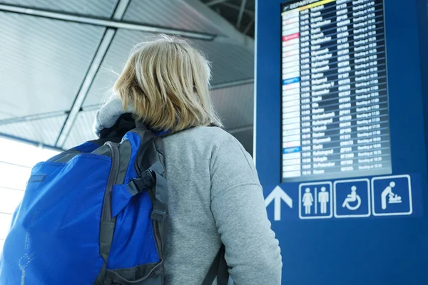 Una mujer con una mochila mira a bordo de salida —  Fotos de Stock