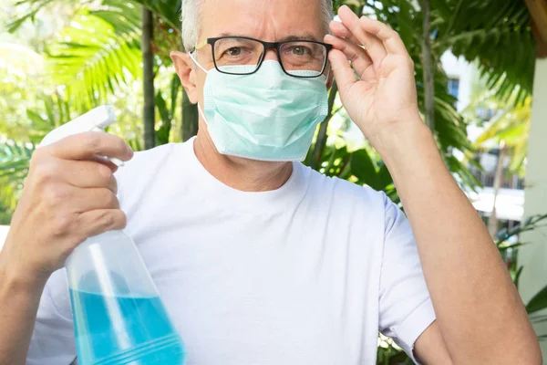 Man with medical face mask is holding a disinfecting alcohol gel — Stock Photo, Image