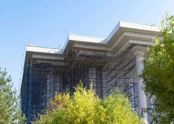 Reconstruction of the building. Scaffolding stands near the building. Town-planning. Subcontractor