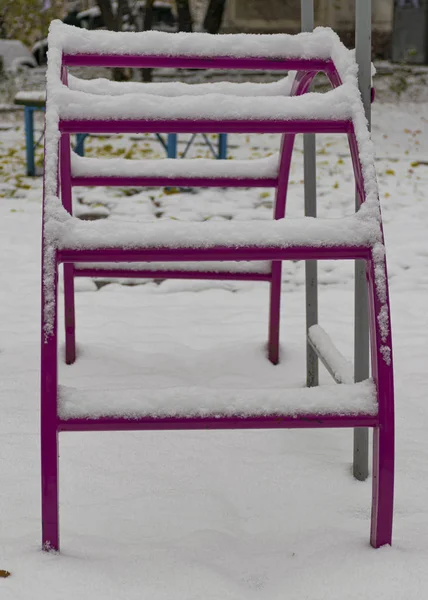 Oyun alanı karla kaplı. Çocuk kaydırağı ve merdivenler. Mutlu çocukluk.