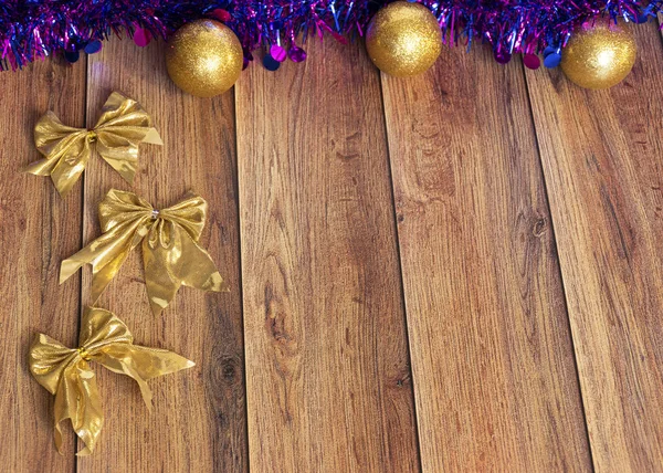 Gifts are packed in kraft paper and tied with a satin ribbon with Christmas toys and purple tinsel on a wooden background. Decor for the Christmas tree.