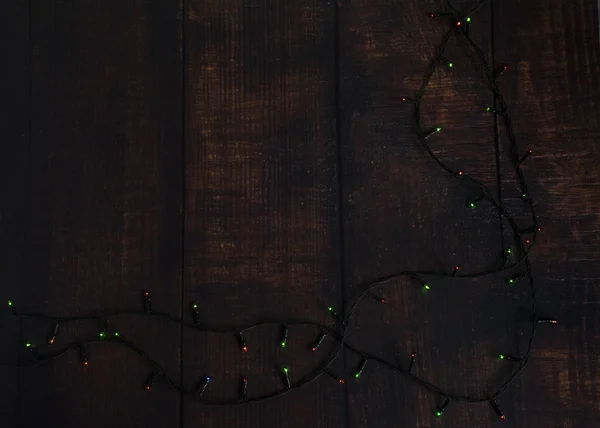 Luci colorate ghirlanda di Natale su sfondo marrone in legno. Luce di Natale con Copyspace per cornice di Capodanno o layout di Natale . — Foto Stock