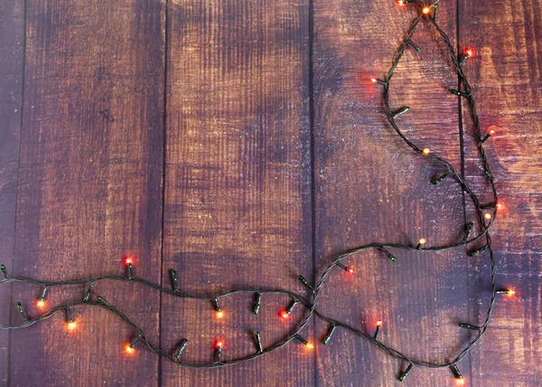 Kolorowe lampki wiankowe na brązowym drewnianym tle. Christmas Light z Copyspace na Nowy Rok ramki lub Christmas Layout. — Zdjęcie stockowe