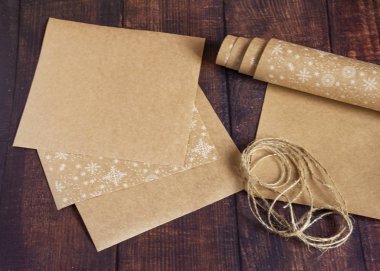 Noel ağacı topları, koniler, bir ip yumağı ve köknar dallarıyla süslenmiş ahşap bir arka planda el yapımı kraft kağıdından yapılmış bir hediye çantası. Noel, Yeni Yıl, Kış tatili.