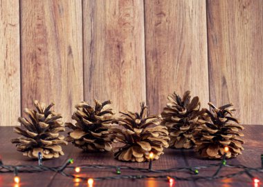 Noel kompozisyonu. Çam kozalakları, bir çelenkle birlikte, eski, ahşap bir arka planda. Düz konum, üst görünüm, kopyalama alanı.