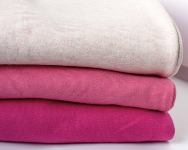 Tahta bir masanın üzerinde bir yığın kalın giysi. Giysiler istiflenmiş. Sıcacık kışlık sonbahar örgü giysileri