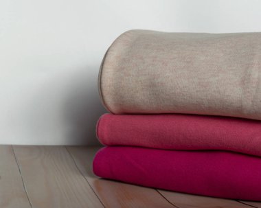 Tahta bir masanın üzerinde bir yığın kalın giysi. Giysiler istiflenmiş. Sıcacık kışlık sonbahar örgü giysileri