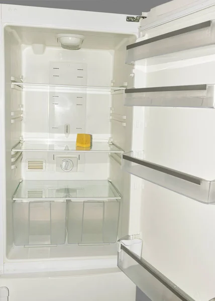 In den leeren Regalen des Kühlschranks liegt ein Stück gelber alter Käse. das Konzept von Ernährung und Hunger. — Stockfoto