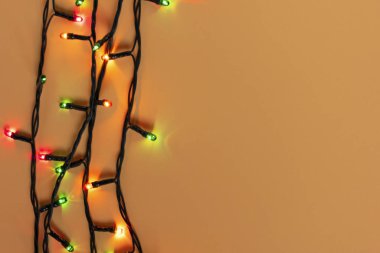 Turuncu arka planda renkli Noel çelengi ışıkları. Yeni yıl aralığı ya da noel planı için telif alanı olan bir Noel ışığı. Noel süslemeleri vitrinleri