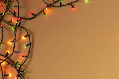 Turuncu arka planda renkli Noel çelengi ışıkları. Yeni yıl aralığı ya da noel planı için telif alanı olan bir Noel ışığı. Noel süslemeleri vitrinleri