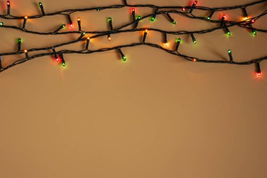 Turuncu arka planda renkli Noel çelengi ışıkları. Yeni yıl aralığı ya da noel planı için telif alanı olan bir Noel ışığı. Noel süslemeleri vitrinleri