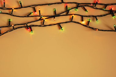 Turuncu arka planda renkli Noel çelengi ışıkları. Yeni yıl aralığı ya da noel planı için telif alanı olan bir Noel ışığı. Noel süslemeleri vitrinleri