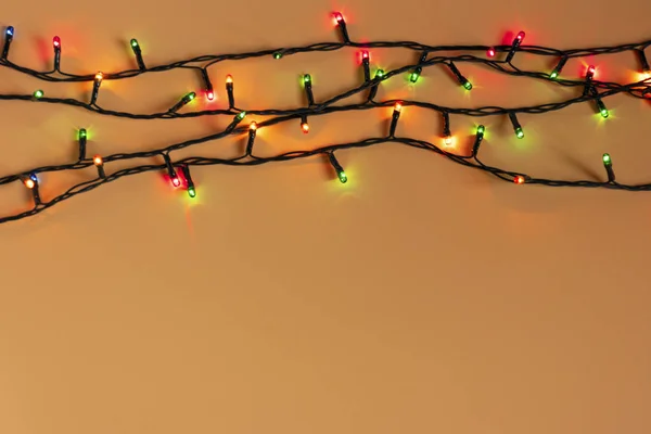 Luci colorate ghirlanda di Natale su uno sfondo arancione. Luce natalizia con copyspace per cornice di Capodanno o layout natalizio. Decorazioni natalizie vetrine — Foto Stock