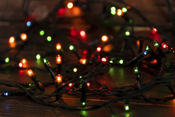 Kolorowe lampki wiankowe na brązowym drewnianym tle. Christmas Light z Copyspace na Nowy Rok ramki lub Christmas Layout. Świąteczne dekoracje gabloty — Zdjęcie stockowe