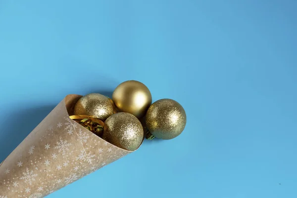 Gouden kerstballen gemorst uit een pakje kraftpapier op een blauwe achtergrond. Kerstballen. Kopieerruimte — Stockfoto