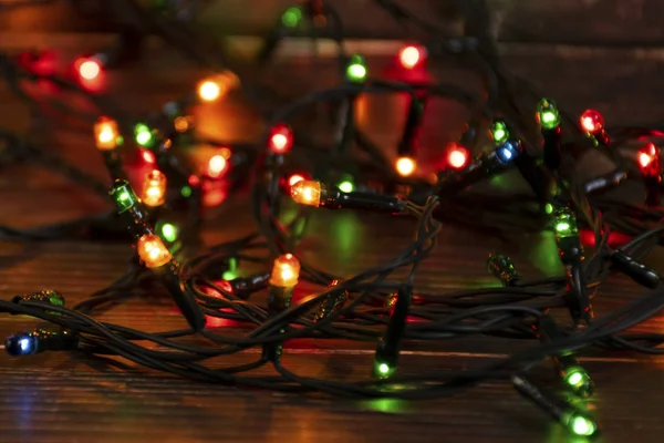 Kolorowe lampki wiankowe na brązowym drewnianym tle. Christmas Light z Copyspace na Nowy Rok ramki lub Christmas Layout. Świąteczne dekoracje gabloty — Zdjęcie stockowe