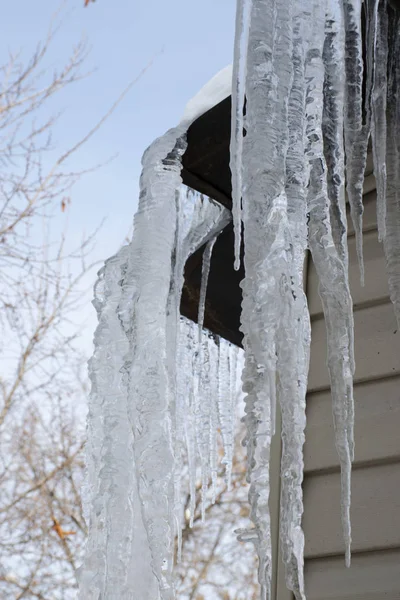 Egy lakóépület tetejéről lógó jégcsapok. A veszélyes nagy jégcsapok télen balesetet okozhatnak. Leesik a jégcsap.. — Stock Fotó