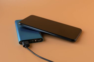 Mobil cihaz ve cihazları şarj etmek için güç bankası. Güç bankası olan mavi akıllı telefon şarj aleti. Kablosuz kulaklıklar ve hoparlörler için dış pil