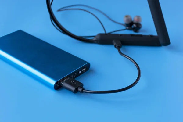 Power bank for charging mobile devices and devices. Blue smartphone charger with power bank. External battery for wireless headphones and speakers — Stock Photo, Image