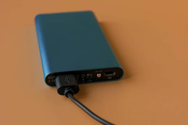 Power bank for charging mobile devices and devices. Blue smartphone charger with power bank. External battery for wireless headphones and speakers