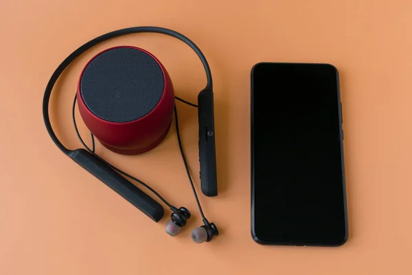 Funkgeräte für das Telefon, schwarze Kopfhörer und ein roter Lautsprecher. Kopfhörer für Handy — Stockfoto