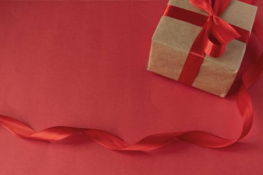 Sevgililer Günü 'nde sevgiline bir hediye. Kırmızı arka planda kırmızı saten kurdeleli Kraft kağıdından bir hediye. Doğum günü. 8 Mart