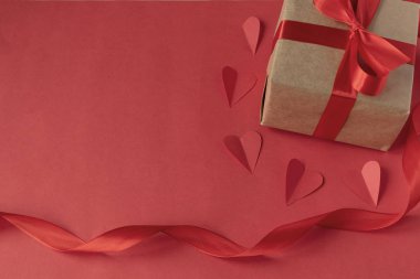 Sevgililer Günü 'nde sevgiline bir hediye. Kırmızı arka planda kırmızı saten kurdeleli Kraft kağıdından bir hediye. Doğum günü. 8 Mart