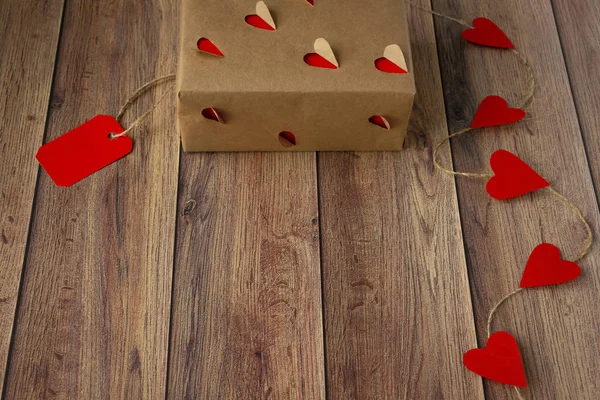 Background for Valentine's Day. Garland of hearts, gift from craft paper on a wooden background. Valentine — Stock Photo, Image