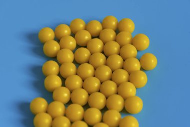 Mavi arka planda sarı vitaminler. Virüse karşı vitamin kompleksi. Sağlık ve bağışıklığı arttırmak için multivitaminler. Tıbbi konsept