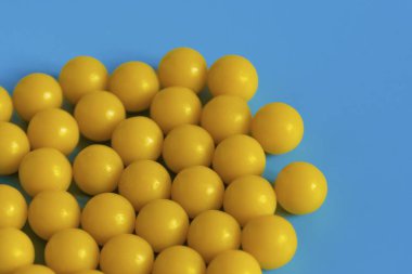 Mavi arka planda sarı vitaminler. Virüse karşı vitamin kompleksi. Sağlık ve bağışıklığı arttırmak için multivitaminler. Tıbbi konsept