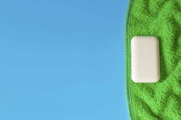 Zachte en donzige handdoeken op een blauwe achtergrond. Zeep voor bad, wasserij en lichaamsverzorging. Persoonlijke hygiëne producten. Badkameraccessoires. — Stockfoto
