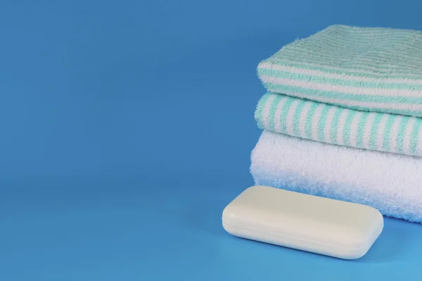 Soft and fluffy towels on a blue background. Soap for bath, laundry and body care. Personal hygiene products. Bathroom accessories.