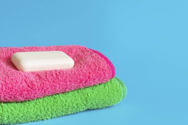 Mavi arka planda yumuşak ve kabarık havlular. Banyo, çamaşır ve vücut bakımı için sabun. Kişisel hijyen ürünleri. Banyo aksesuarları..