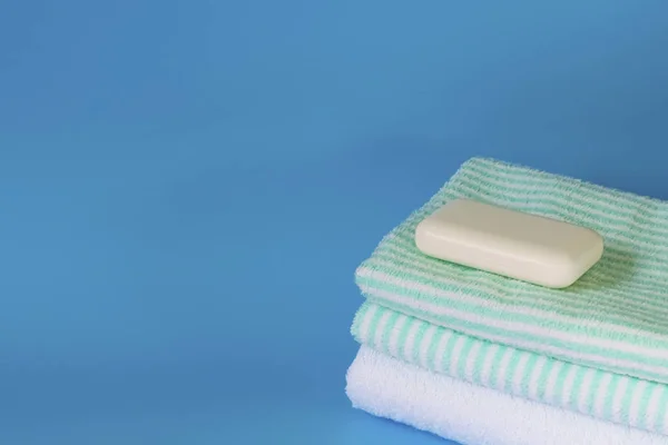 Toallas suaves y esponjosas sobre un fondo azul. Jabón para baño, lavandería y cuidado corporal. Productos de higiene personal. Accesorios de baño . —  Fotos de Stock