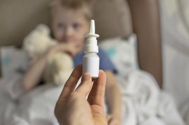 Ateşi ve baş ağrısı olan hasta üzgün bir çocuk yatakta yatıyor, ilaç ve hap içmeyi reddediyor. Grip salgını virüsü bakterisi