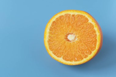 Mavi arka planda olgun, sulu bir portakal. Citrus meyvesi. Vejetaryenler için vitamin ve yiyecek..