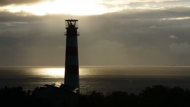 Leuchtturm auf dem Meer unter stürmischen Wolken und mit dem Schiff im Hintergrund — Stockvideo