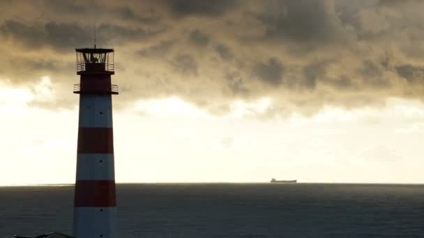 Zeitraffer-Leuchtturm auf dem Meer unter stürmischen Wolken und mit dem Schiff im Hintergrund — Stockvideo