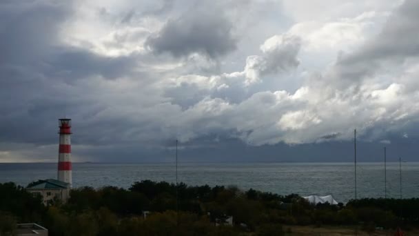 Buque de carga pasa por un hermoso faro majestuoso bajo nubes tormentosas dramáticas — Vídeos de Stock