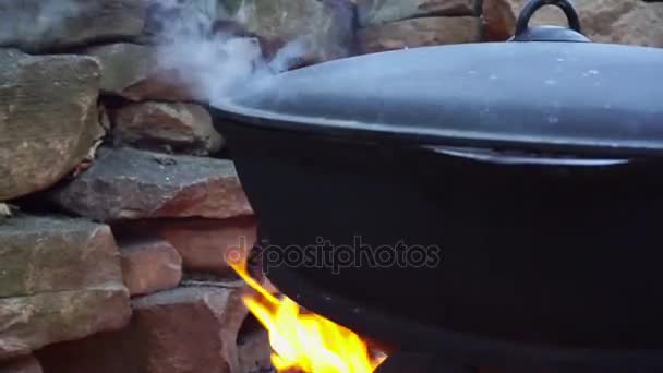 Memasak daging di atas api dalam kuali besi cor . — Stok Video