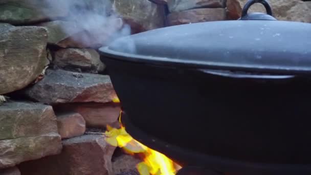 Memasak daging di atas api dalam kuali besi cor . — Stok Video