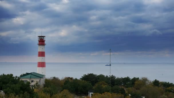 Buque de carga pasa por un hermoso faro majestuoso bajo nubes tormentosas dramáticas — Vídeo de stock