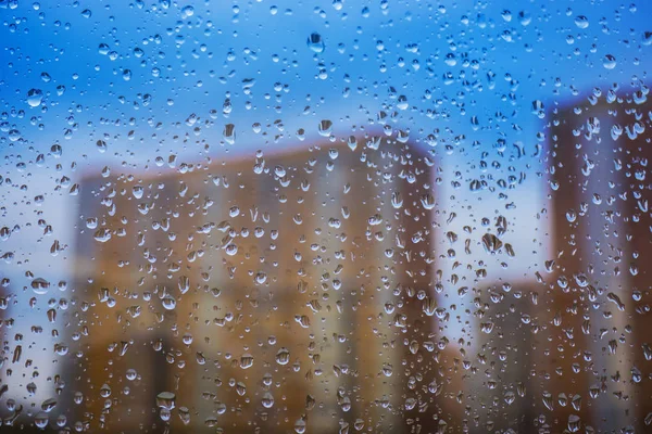 Sfondo astratto. Gocce d'acqua sulla finestra. grattacieli . — Foto Stock