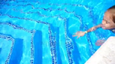 Güzel küçük kız havuzda yüzüyor ve eğleniyor.