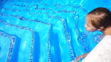 Güzel küçük kız havuzda yüzüyor ve eğleniyor.